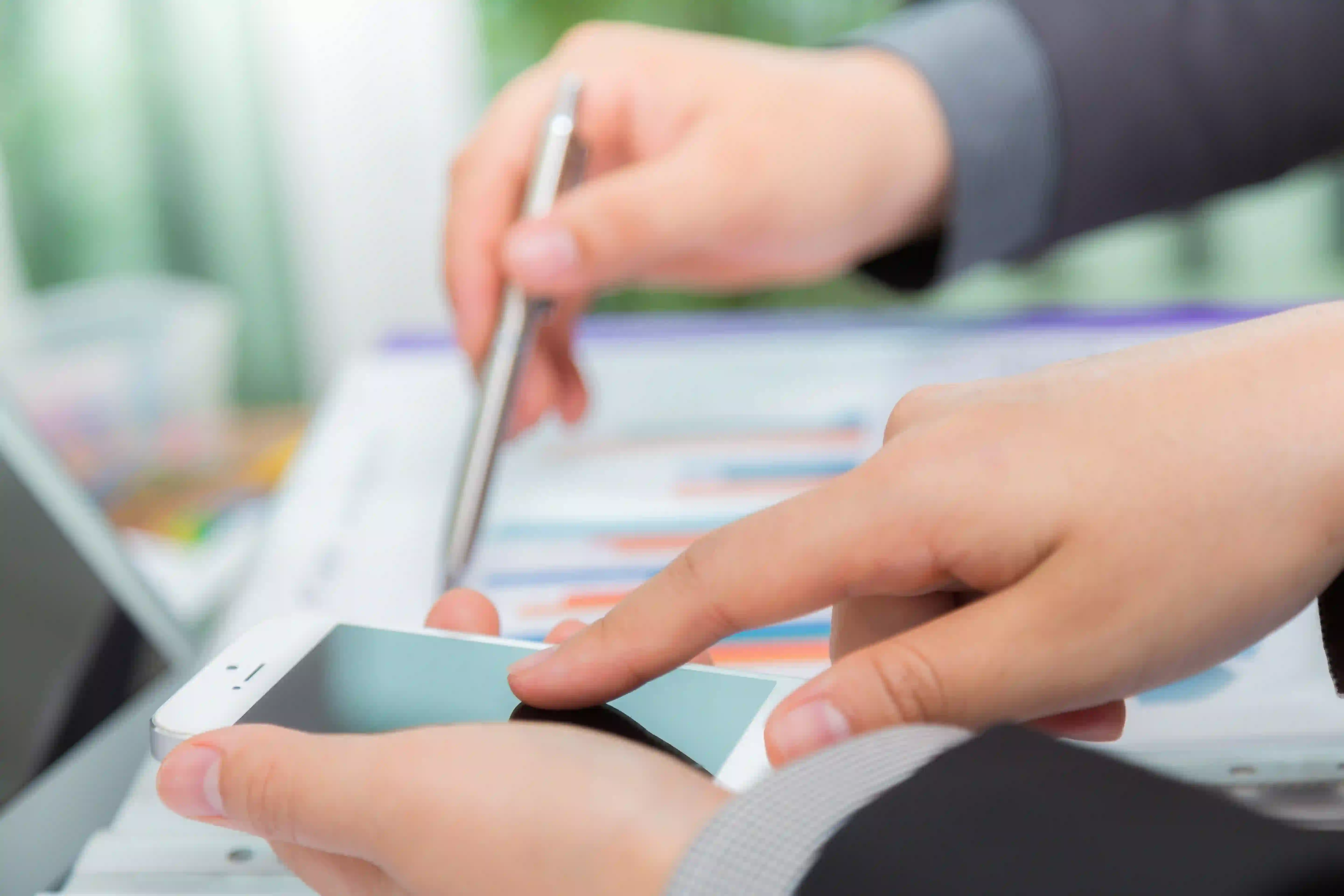 Personas comparando datos financieros entre un gráfico y el móvil